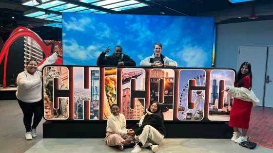 Group of young people standing around a Chicago sign